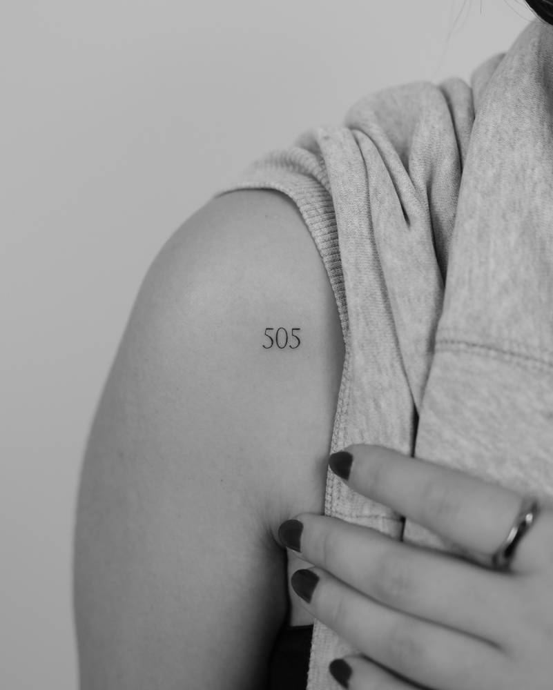 Serif font number "505" tattoo located on the shoulder.