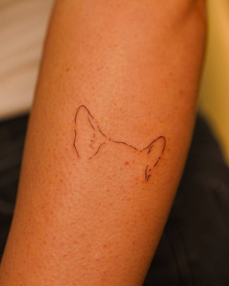 Dog ears tattoo in fine line style placed on the forearm.