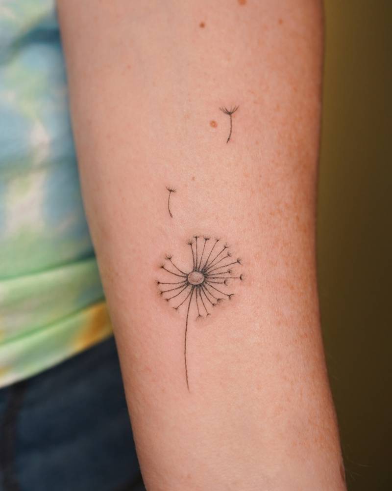 Dandelion tattoo located on the inner forearm, illustrative style.