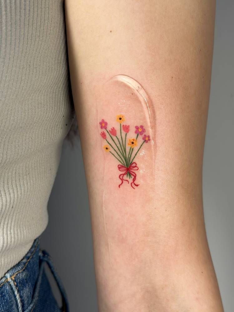 Illustrative style flower bouquet tattoo located on the inner arm.