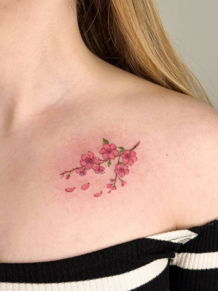 Watercolor style cherry blossom tattoo located on the collarbone.