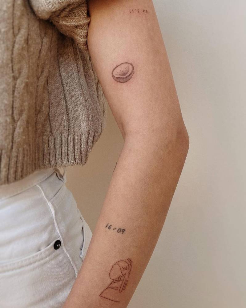 Coconut and 'Girl with a Pearl Earring' tattoos located on the arm./
