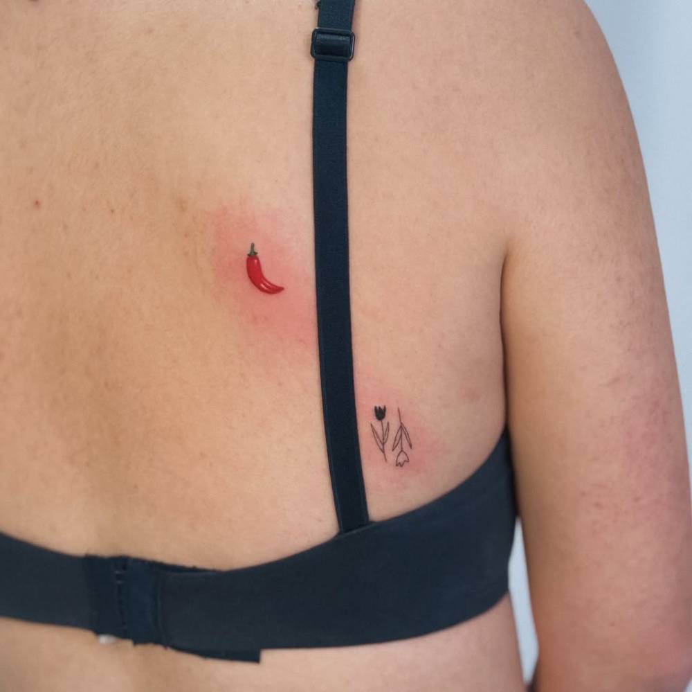 Red chili and tulips tattoos located on the back.