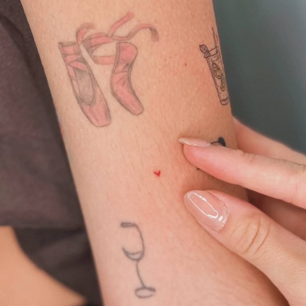 Tiny minimalistic red heart tattoo located on the upper arm.