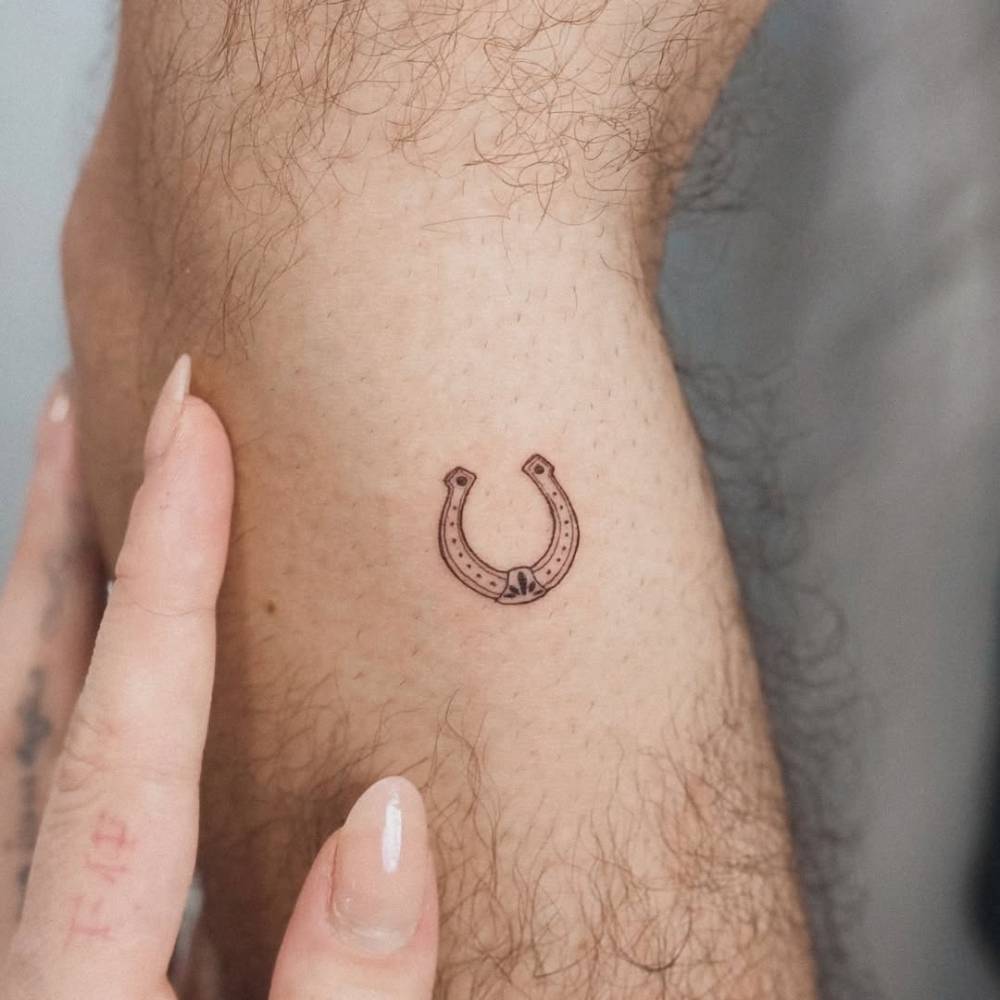 Horseshoe tattoo in illustrative style done on the forearm.