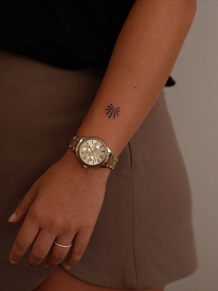 Minimalistic style ornamental tattoo located on the wrist.