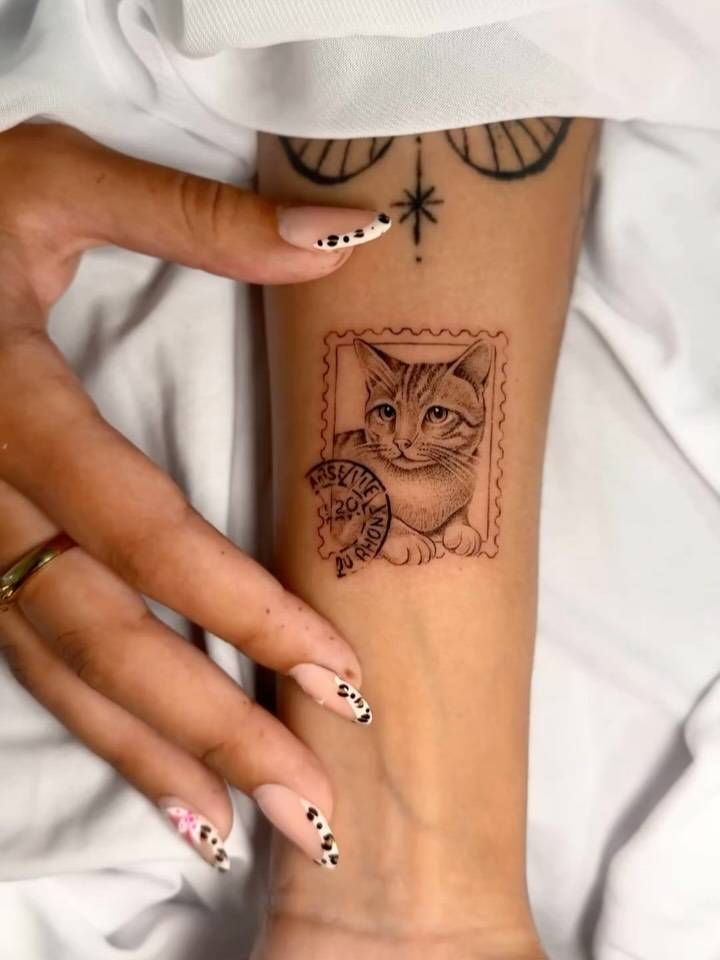 Cat stamp tattoo in micro-realistic style located on the inner forearm.