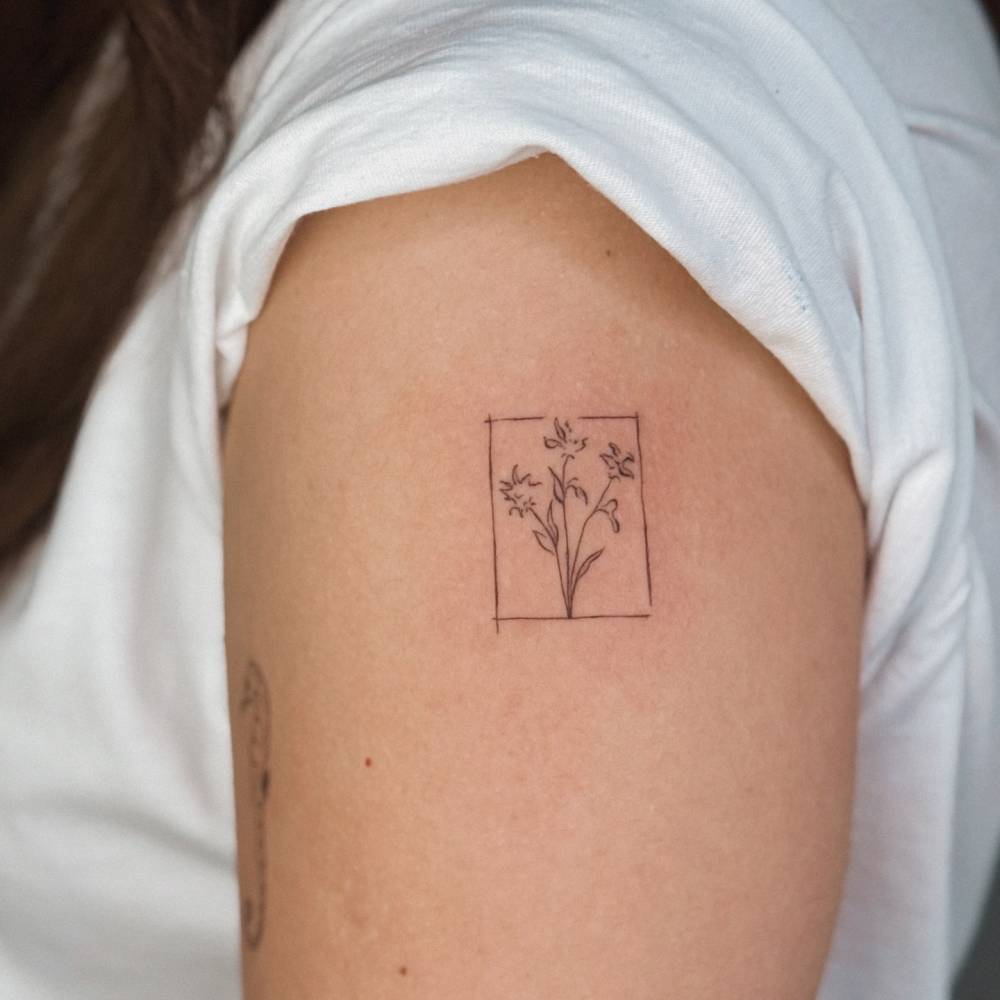 Tiny fine line flowers tattoo placed on the upper arm.