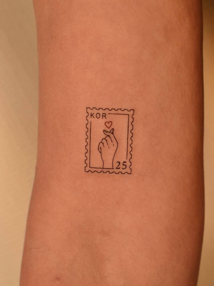 Korean finger heart stamp tattoo located on the bicep.
