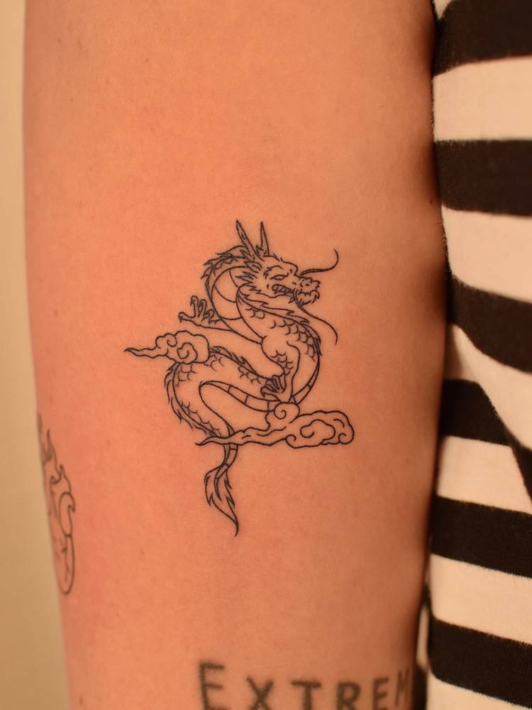 Fine line style dragon tattoo located on the inner forearm.