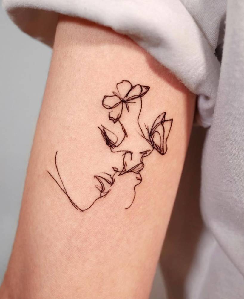 Sketch work style butterfly woman tattoo located on the tricep.