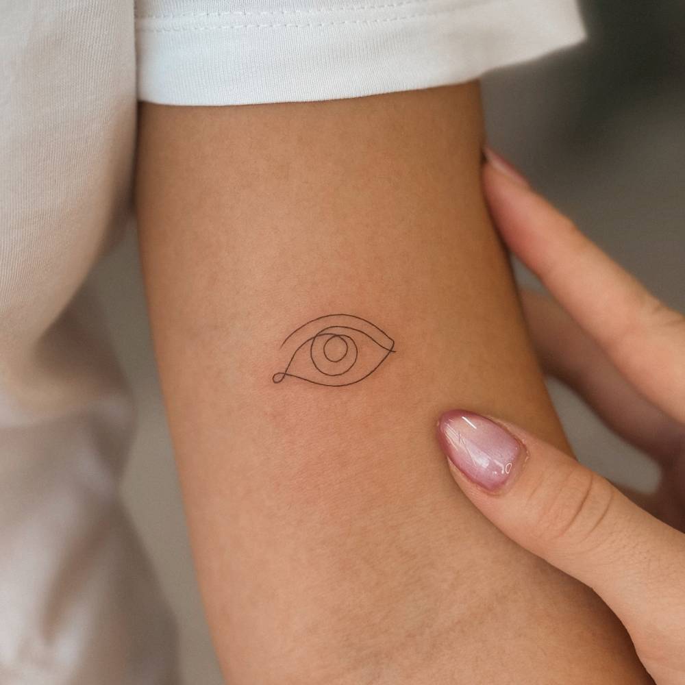 One line eye tattoo located on the bicep.