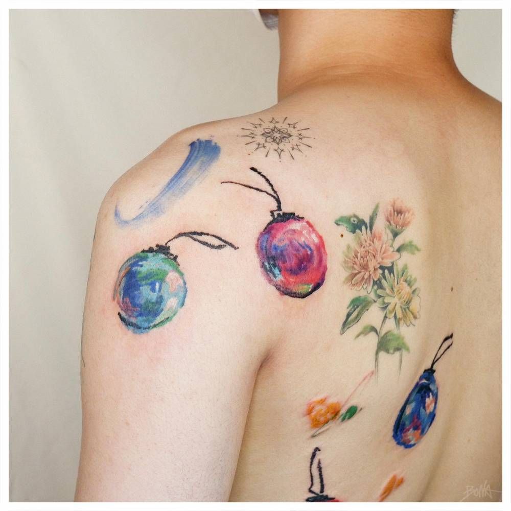 Watercolor style Christmas balls tattooed on the back.
