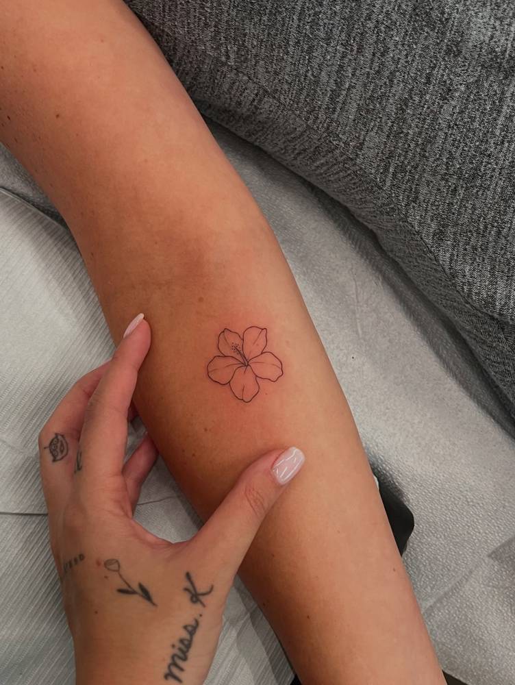 Hibiscus flower tattoo located on the inner forearm, fine line style.