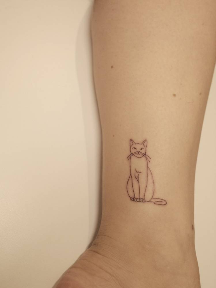 Little cat in fine line style tattooed on the wrist.