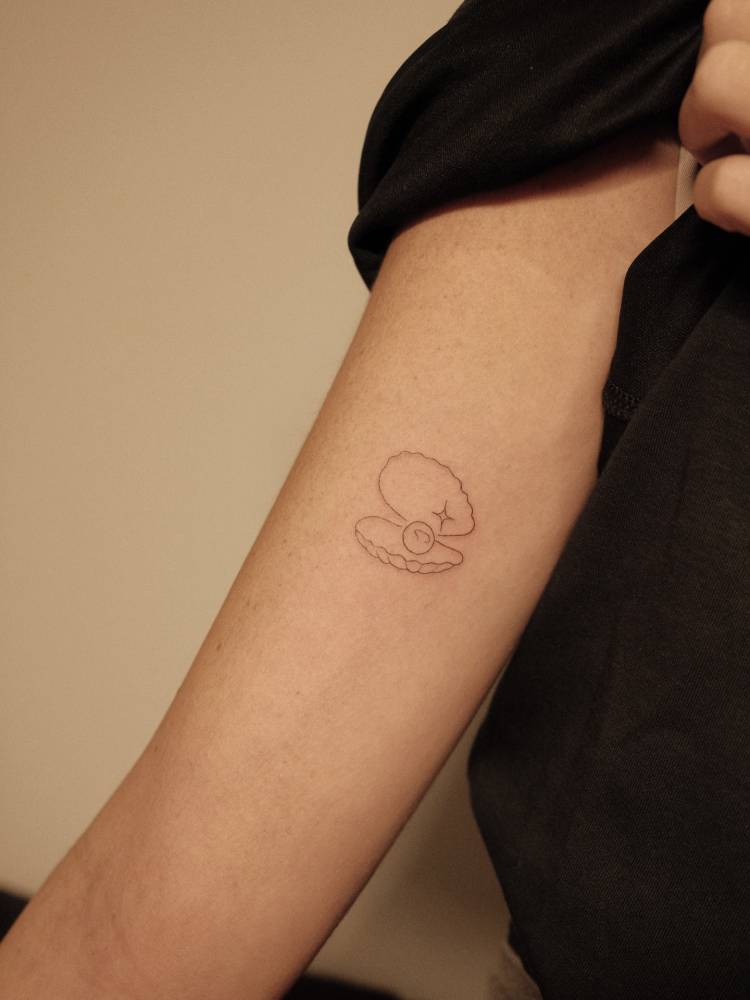 Tattoo of a scallop in fine line style placed on the inner arm.