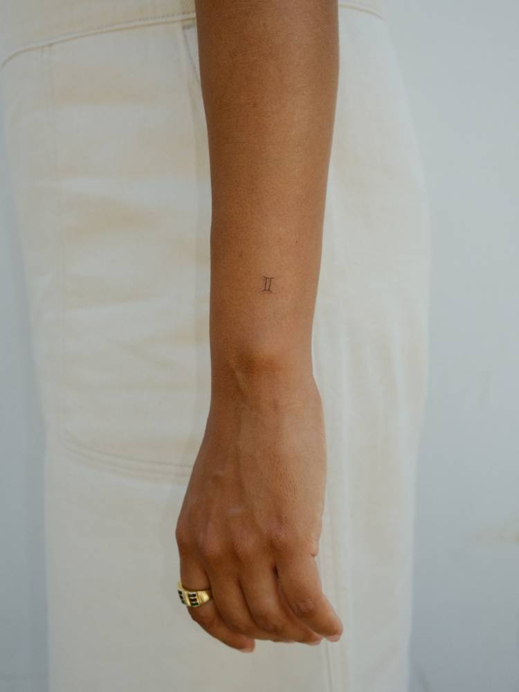 Tiny minimalistic Gemini zodiac symbol tattooed on the wrist.