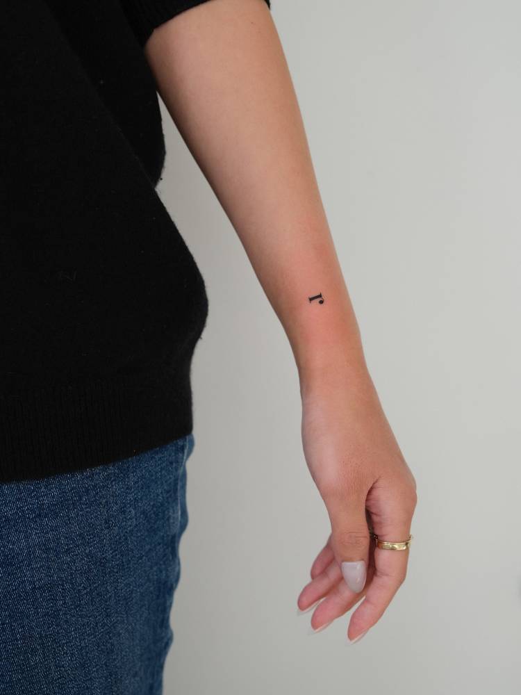 Serif font letter "R" tattoo placed on the wrist.