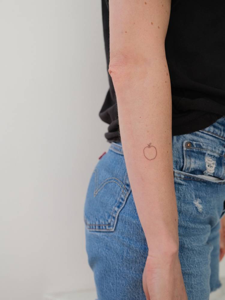 Apple tattoo in minimalistic style located on the forearm.