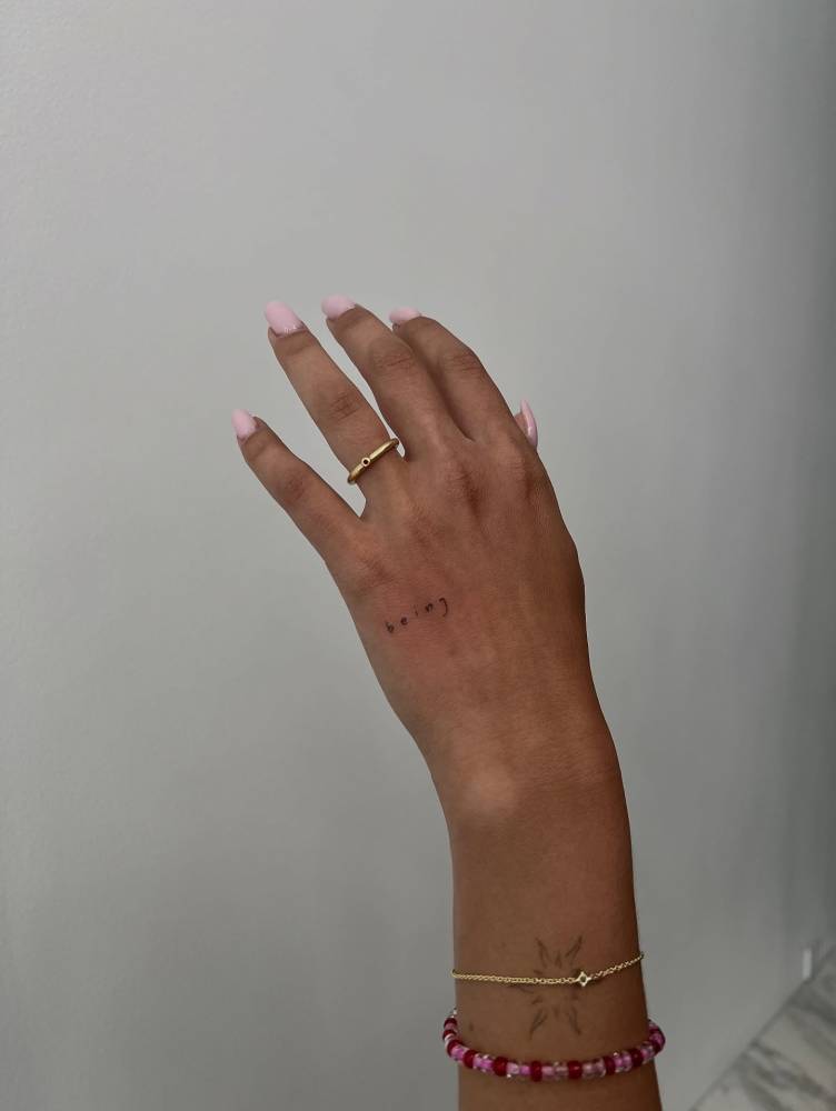 Lettering tattoo that says "being" located on the hand.