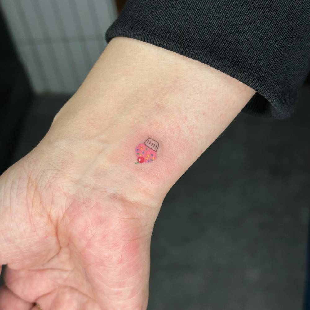 Cute cupcake tattoo hand poked on the wrist.