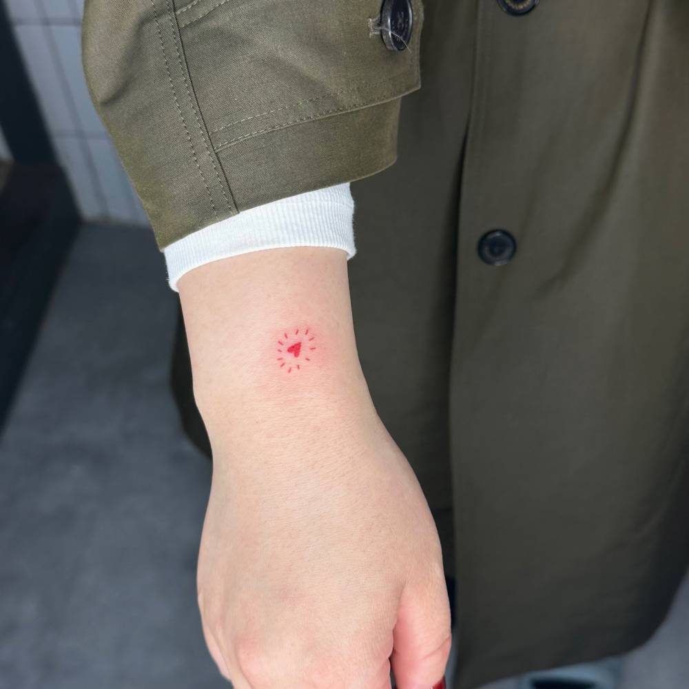 Hand poked tiny red heart tattoo done on the wrist.
