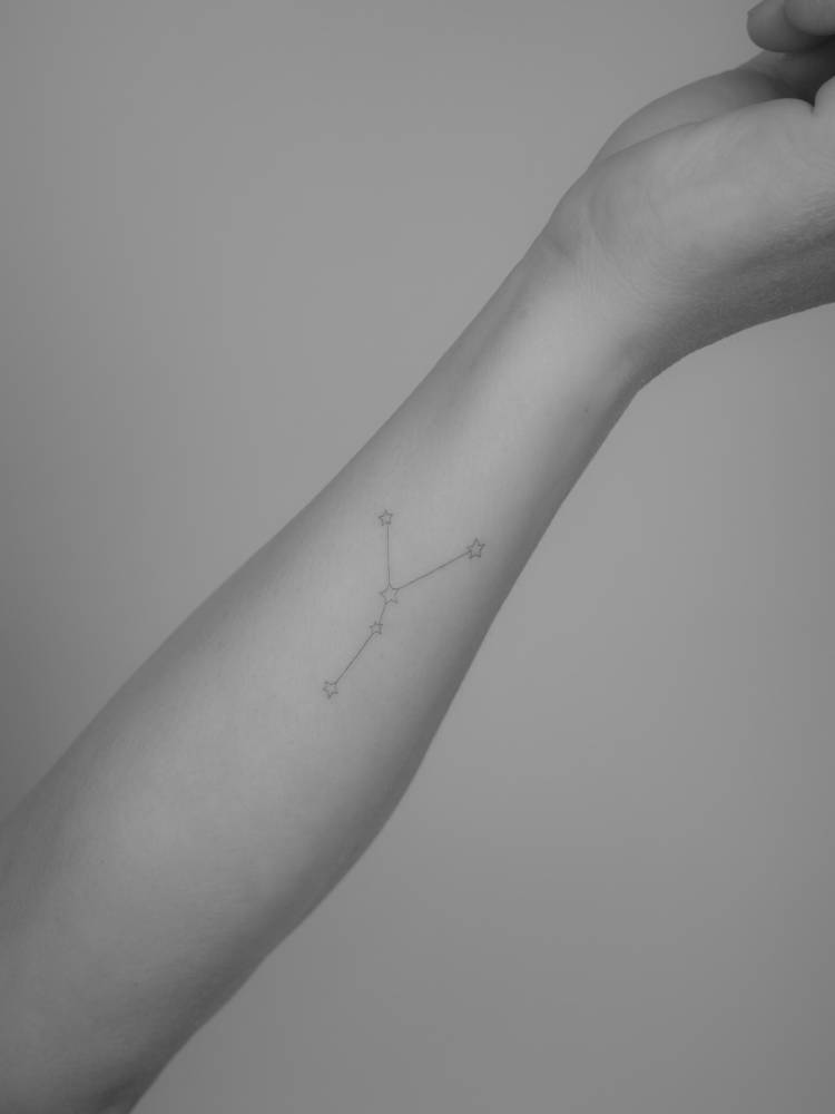 Fine line style Cancer constellation tattoo located on the inner forearm.