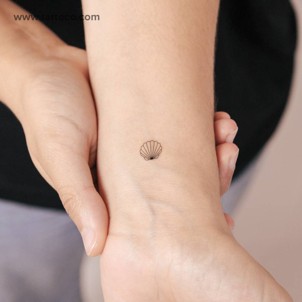 Tiny scallop shell semi-permanent tattoo placed on the wrist.