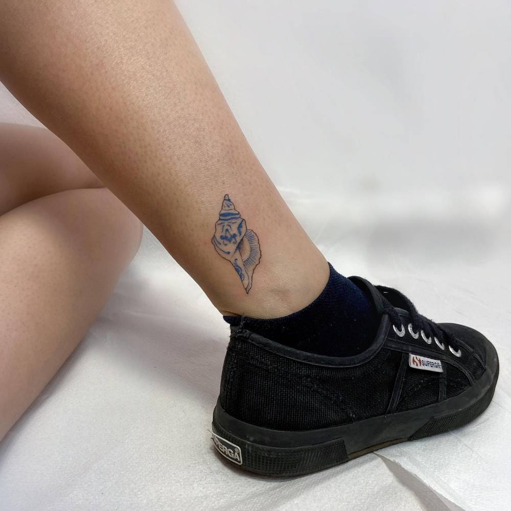 Porcelain tulip shell tattoo placed on the ankle.
