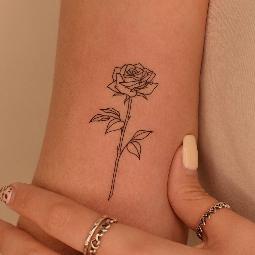 Fine line rose tattoo located on the inner arm.