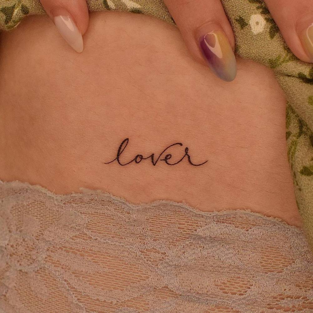 Tattoo of the word "lover" located on the hip.
