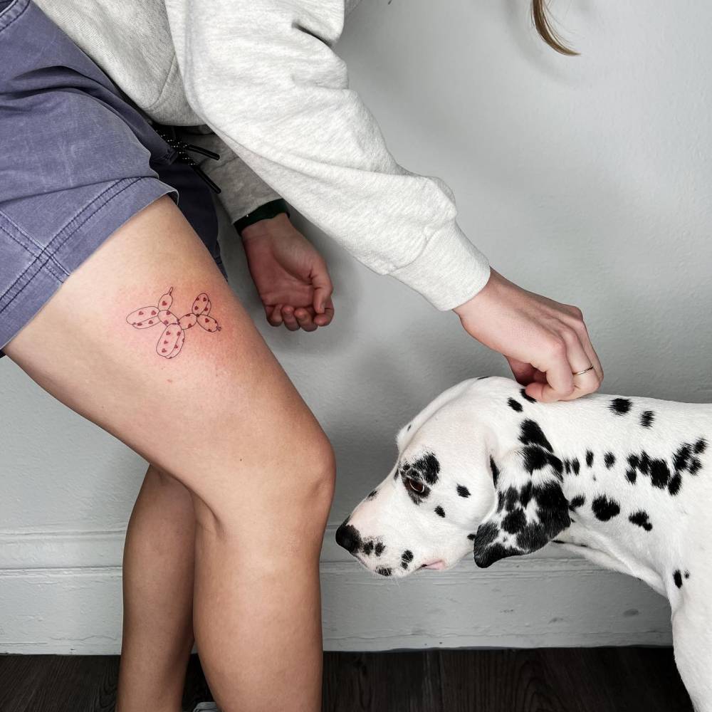 Balloon dog tattoo located on the thigh.
