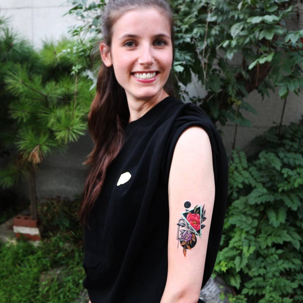 Graphic style peony tattoo located on the upper arm.
