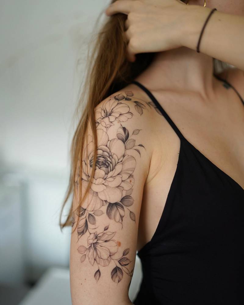 Illustrative style peony and magnolia tattoo located on the upper arm.