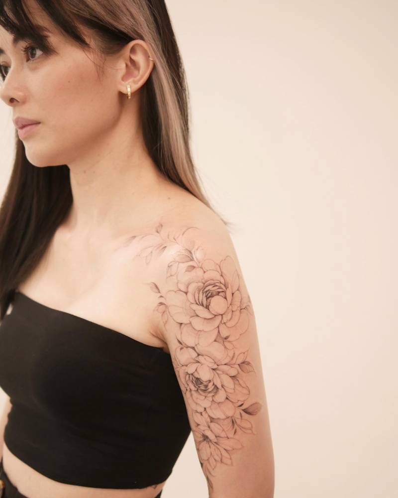 Peonies tattoo located on the upper arm, illustrative style.