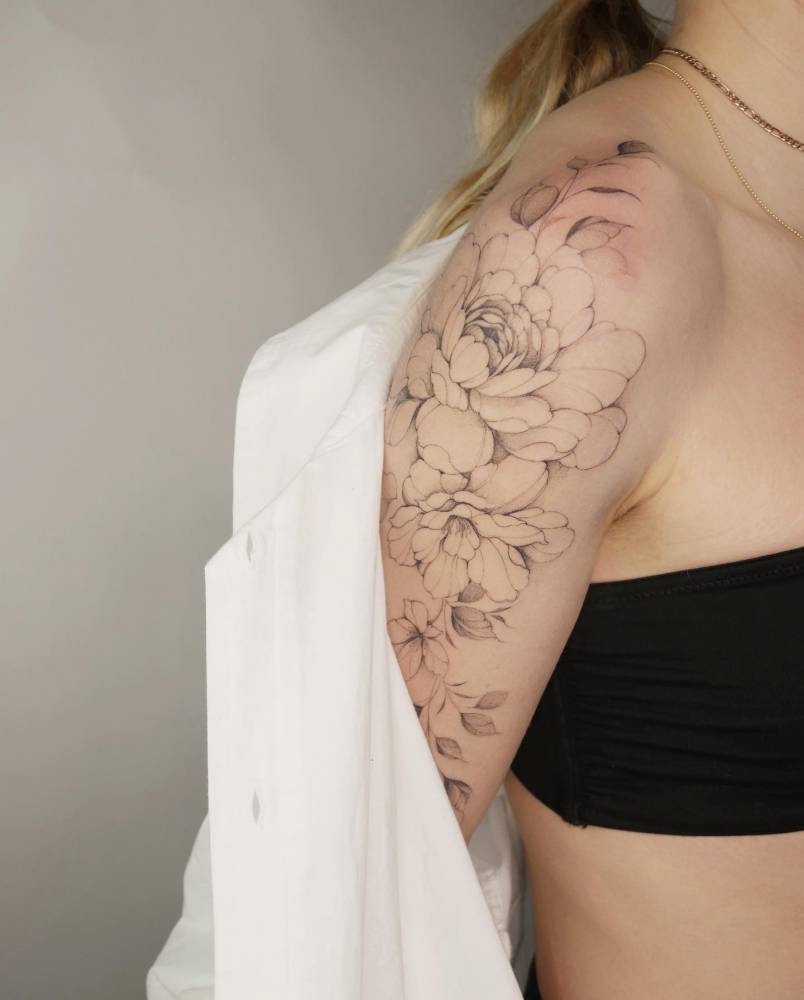 Peony and magnolia tattooed on the upper arm.