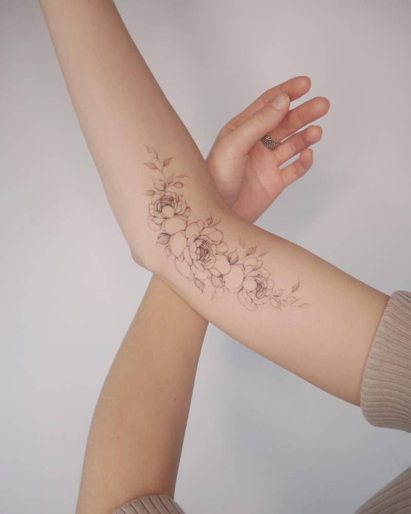 Peonies tattoo located on the arm, illustrative style.