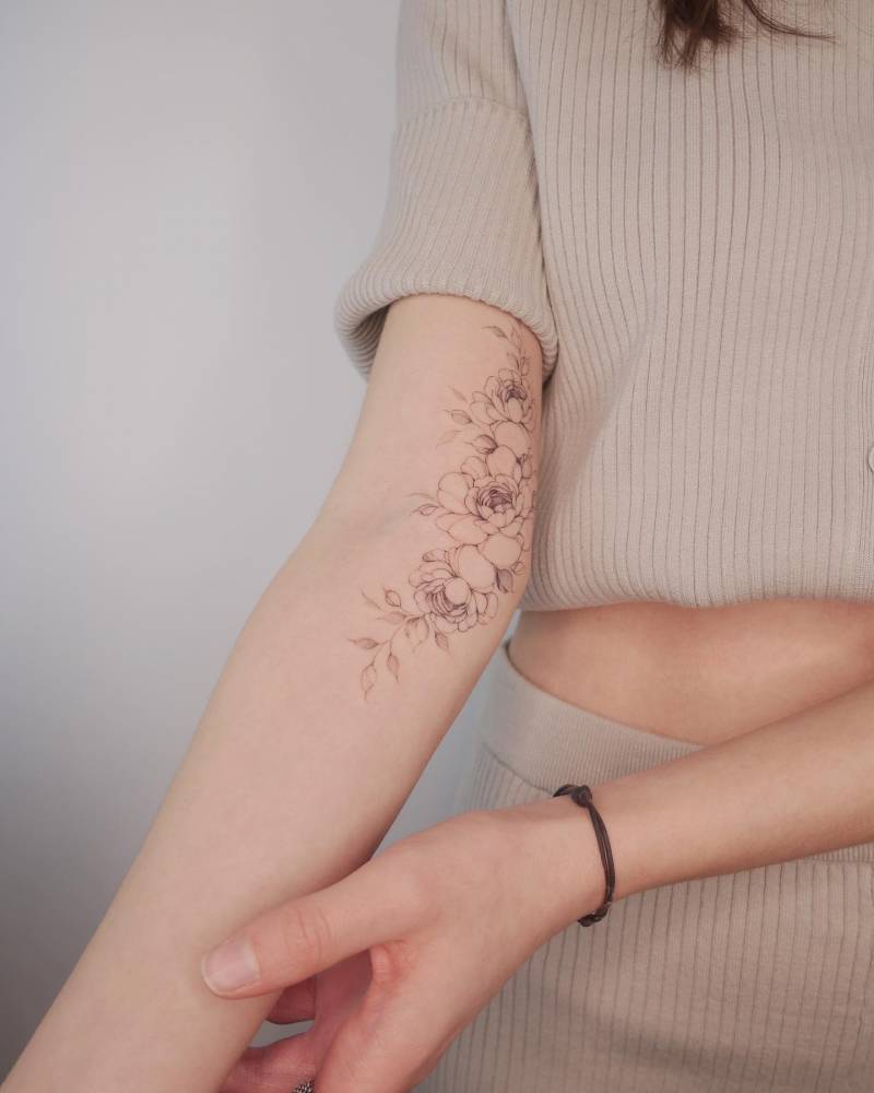 Peonies tattoo located on the arm, illustrative style.
