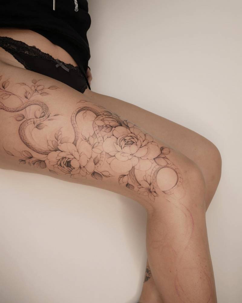 Huge snake and peonies tattoo located on the thigh.