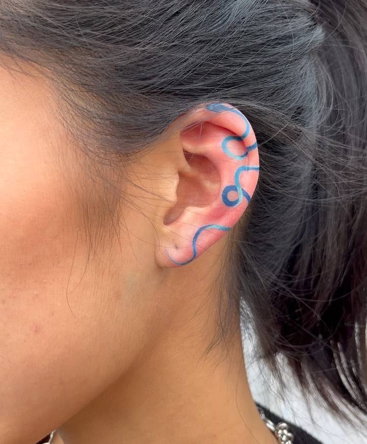 Blue snake tattoo located on the ear.