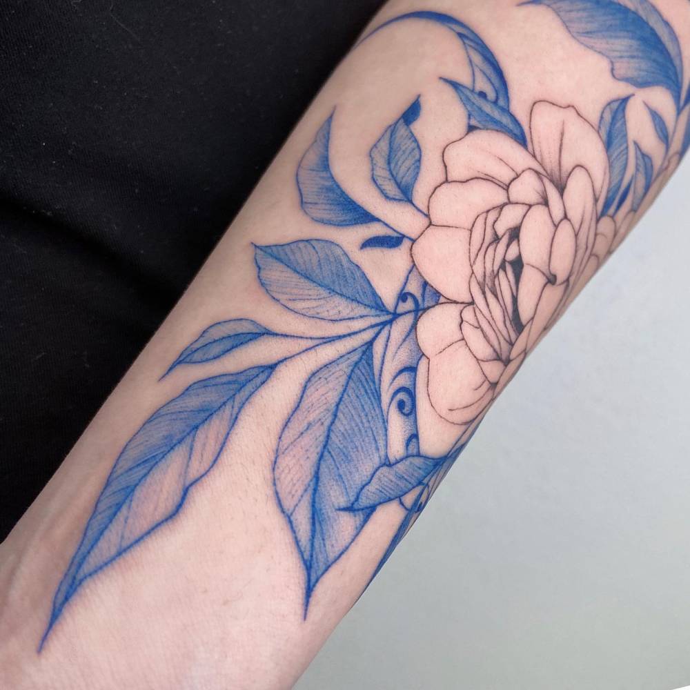 Peony and porcelain snake tattooed on the forearm.