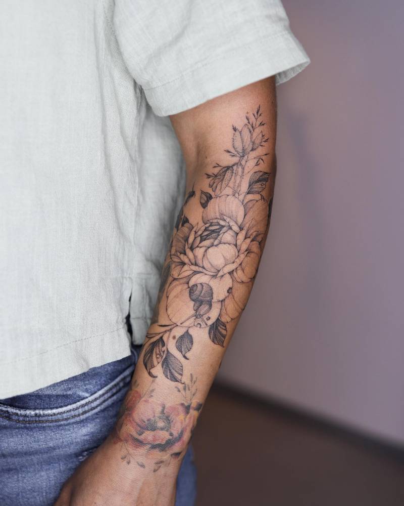 Freehand peony and snail tattoo located on the forearm.