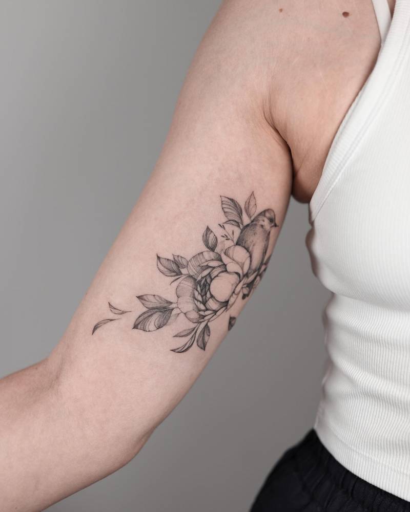 Peony and bird tattoo located on the inner arm, illustrative style.