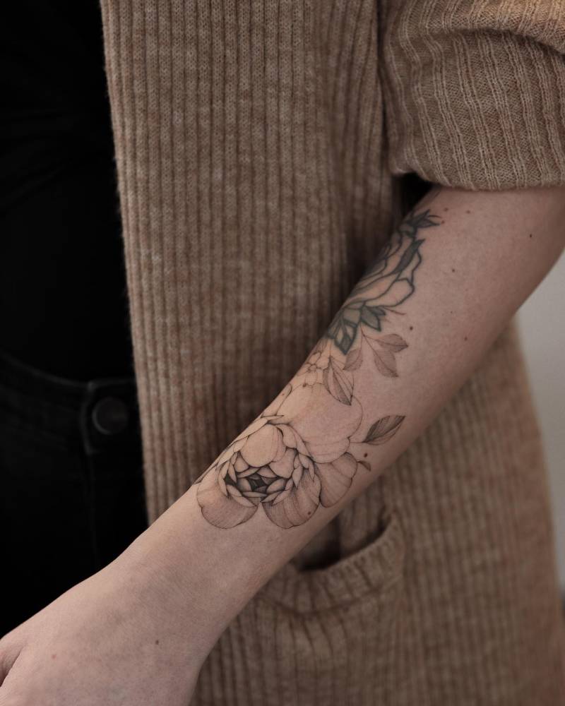 Illustrative style freehand peony tattoo located on the forearm.