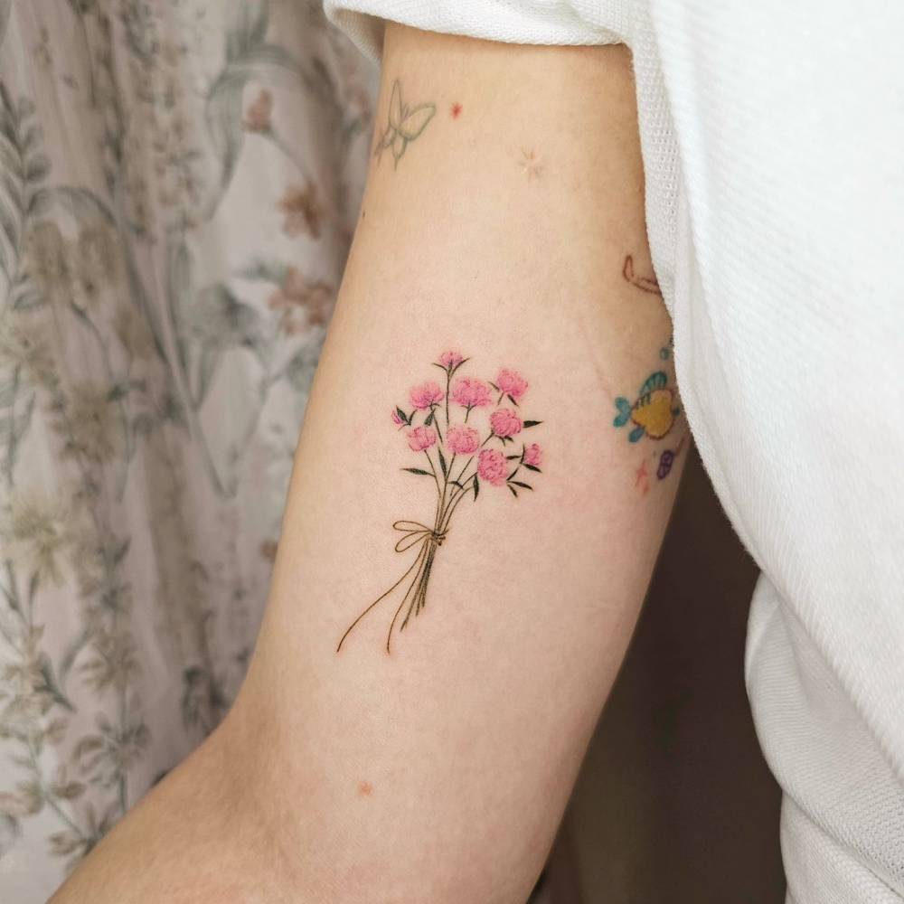 Pink peony bouquet tattoo in watercolor style located on the inner arm.