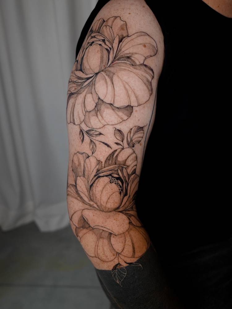 Peony flowers tattoo located on the upper arm, illustrative style.