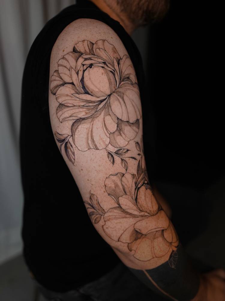 Peony flowers tattoo located on the upper arm, illustrative style.