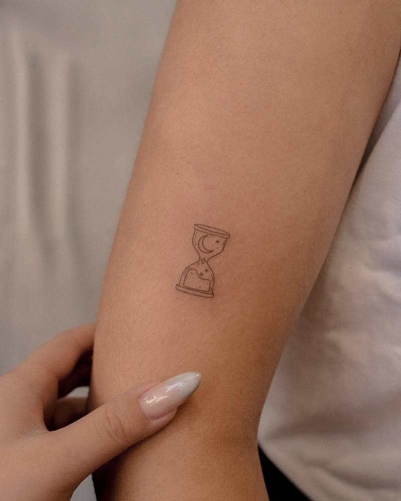 Hourglass tattoo in fine line style placed on the upper arm.