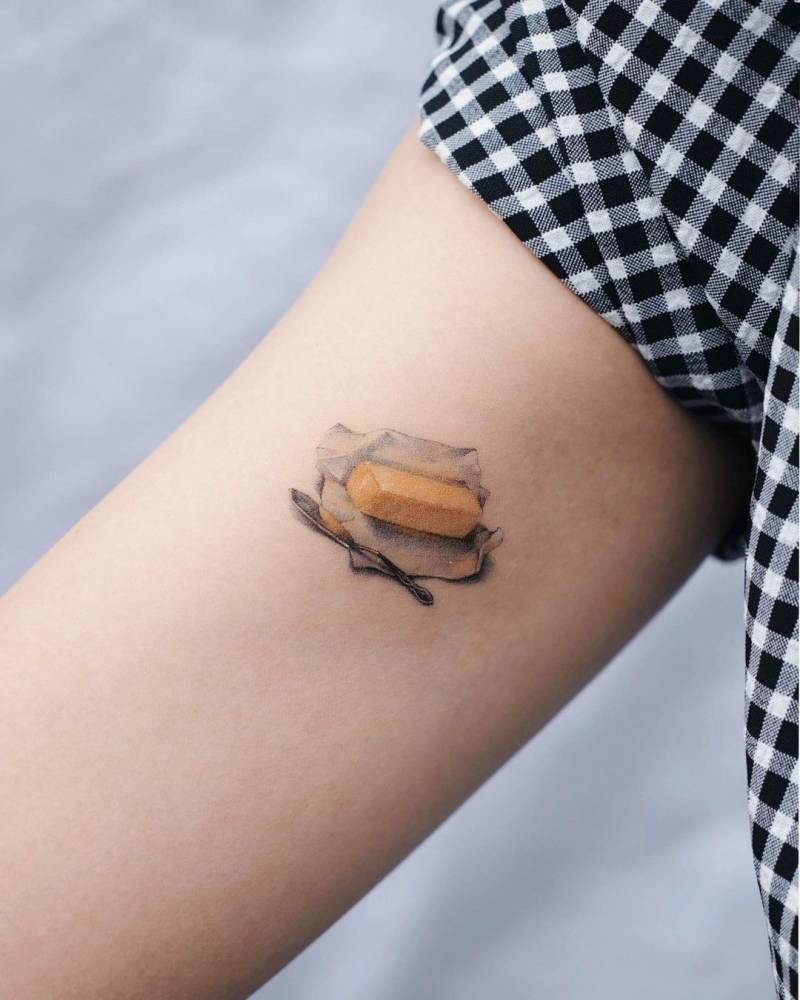 Micro-realistic butter tattoo on inner arm