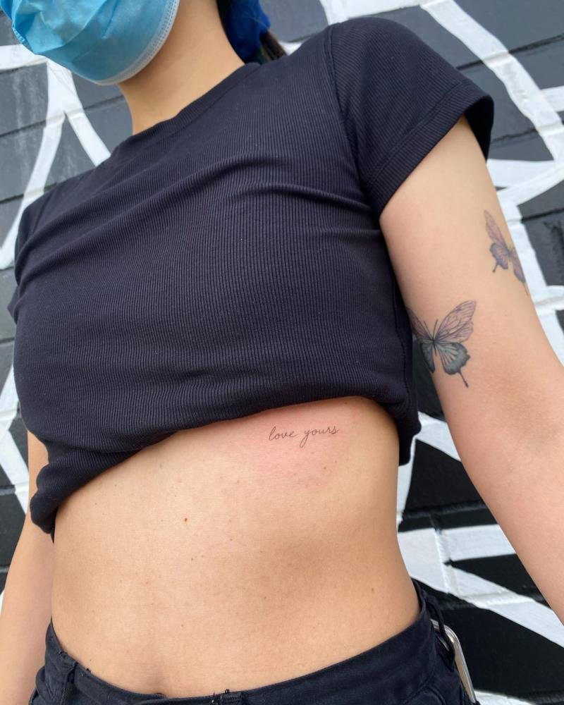 "Love yours" lettering tattoo handwritten on the rib.